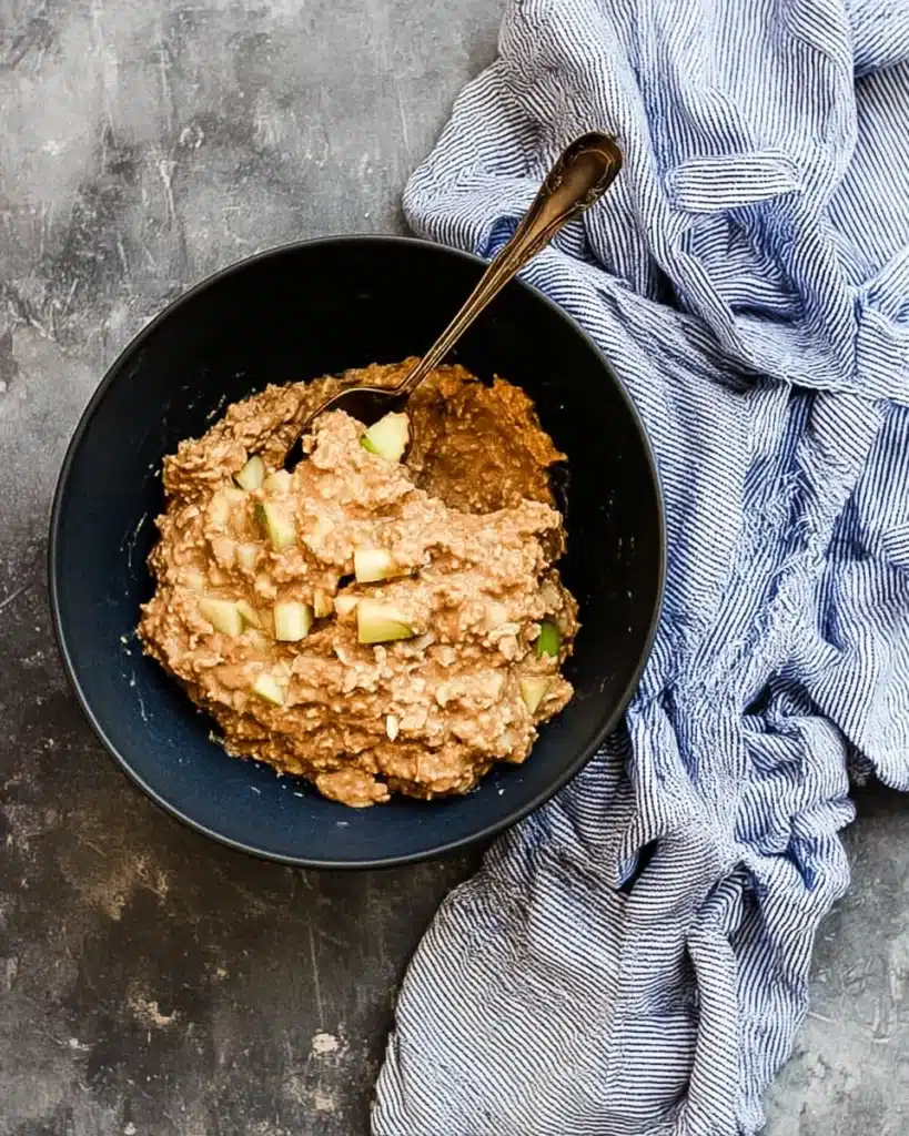Cinnamon Apple Oatmeal Muffins 3 Thick cinnamon apple oatmeal muffin batter with apples and oats in a bowl