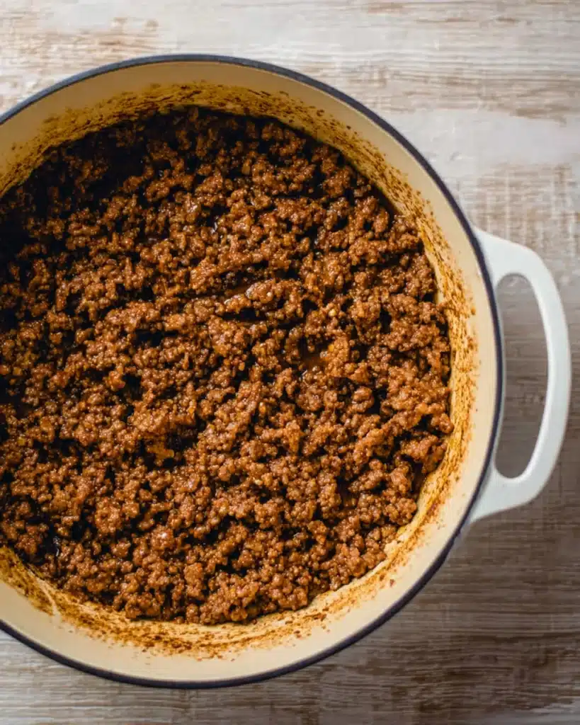 Browned ground beef in a white pot for Easy Taco Soup