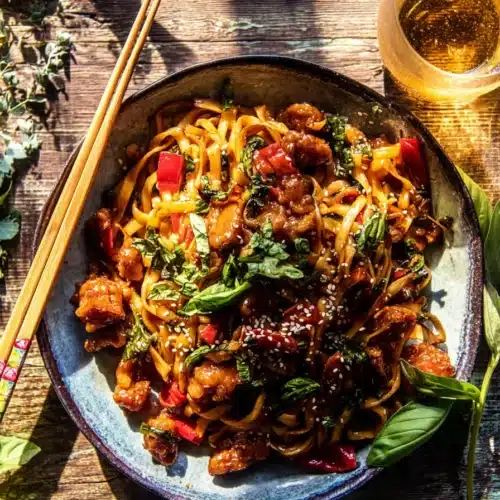 Garlic Chicken Noodles: A Fast, Flavor-Packed Dinner in 20 Minutes 6 Garlic chicken noodles with crispy chicken, basil, and sesame seeds on a rustic table