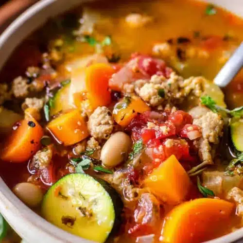 Ground turkey vegetable soup with colorful vegetables and herbs in a rustic bowl