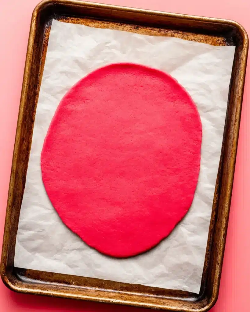 Rolled pink heart cookies dough on parchment paper