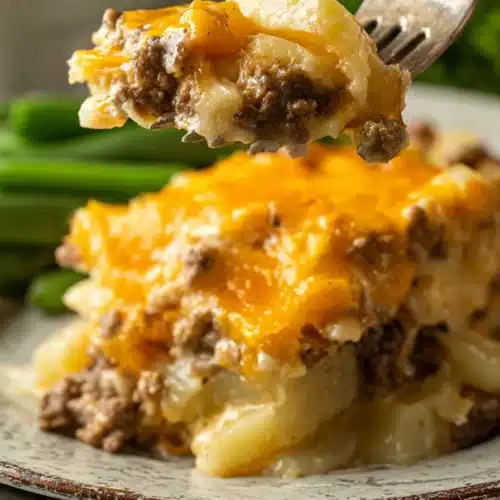 Fork holding cheesy Hobo Casserole with ground beef, potatoes, and melted cheese on a rustic plate