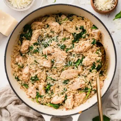 Creamy one pot chicken orzo with spinach in a white pot on kitchen table