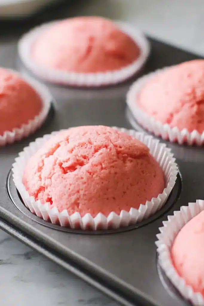 Pink Velvet Cupcakes 2 Freshly baked pink velvet cupcakes in white liners in muffin pan