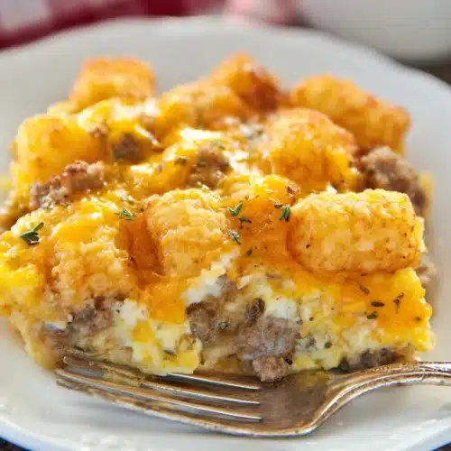 Tater Tot Sausage Breakfast Casserole – The Ultimate Comfort Breakfast 3 Tater Tot Sausage Breakfast Casserole with melted cheese and golden tater tots on a white plate