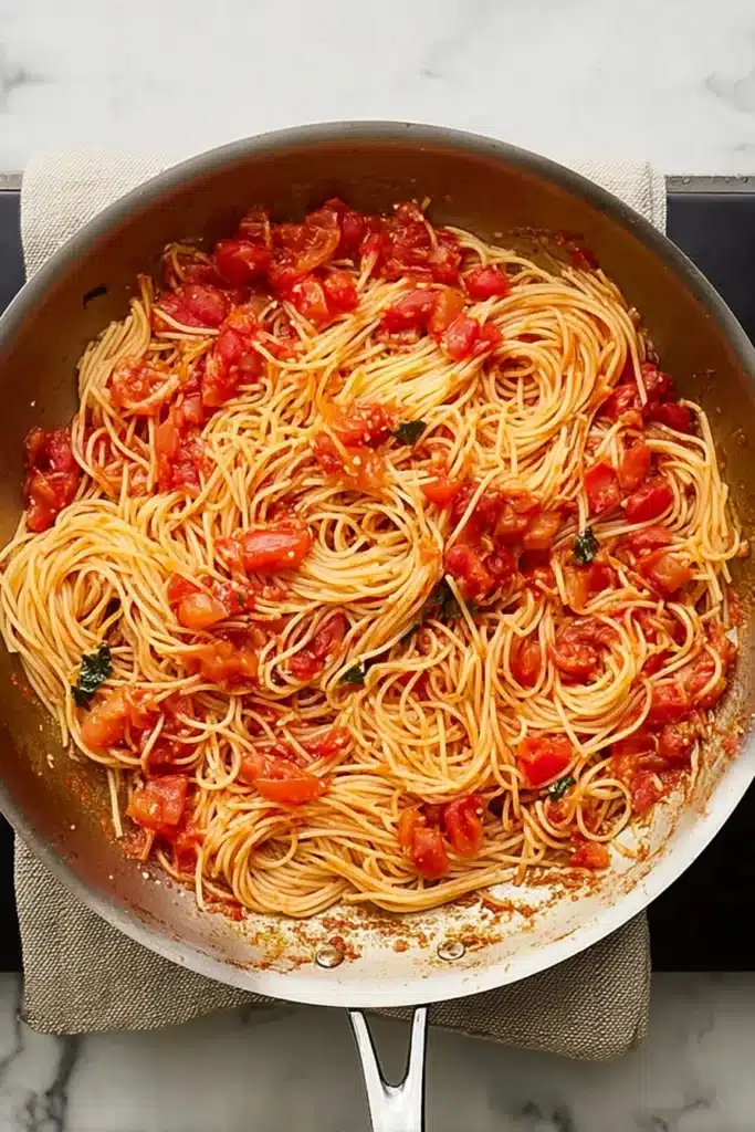 Angel hair pasta tossed in tomato and garlic sauce in a skillet
