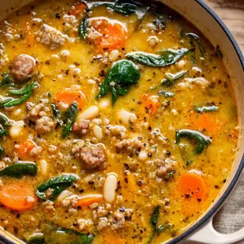 Tuscan white bean soup with sausage, carrots, and spinach in a creamy golden broth