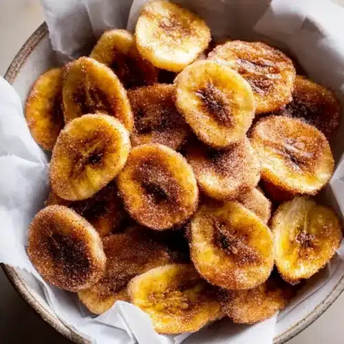 Air Fryer Cinnamon Banana Chips (Crispy, Healthy, and Ready in 15 Minutes) 4 Crispy air fryer cinnamon banana chips in a bowl on parchment paper