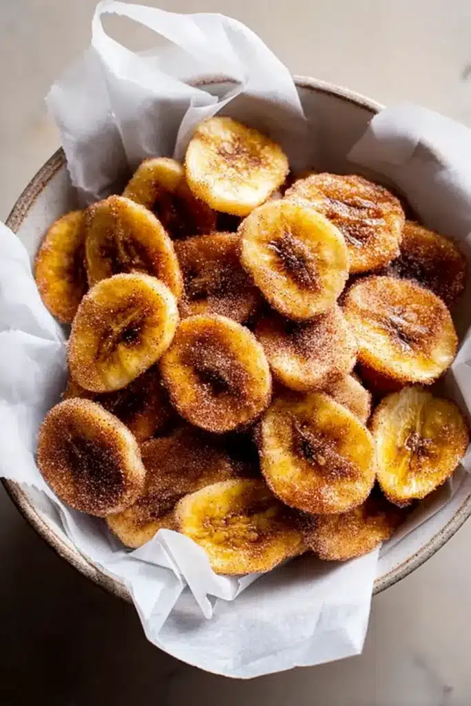 Air Fryer Cinnamon Banana Chips (Crispy, Healthy, and Ready in 15 Minutes) 1 Crispy air fryer cinnamon banana chips in a bowl on parchment paper