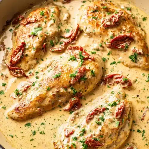 Creamy Cajun chicken in a skillet with sun-dried tomatoes and creamy sauce