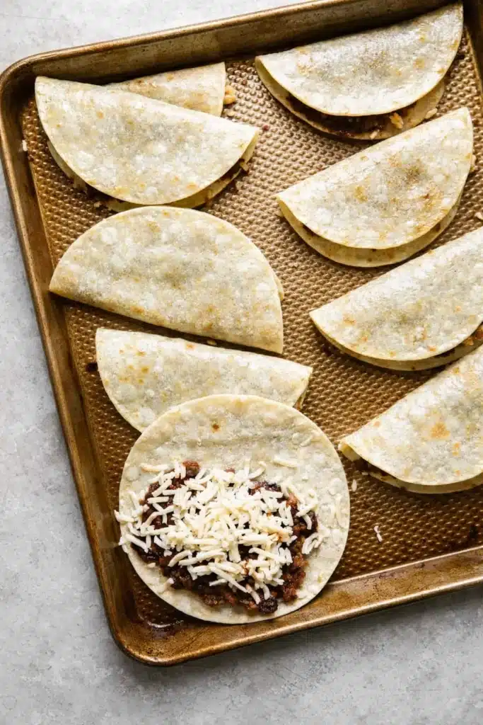Unbaked black bean tacos with cheese on baking sheet