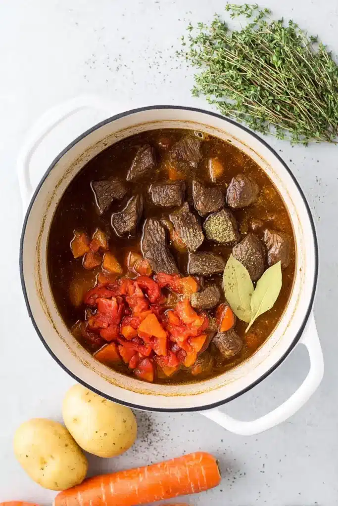 Dutch oven with beef, tomatoes, and herbs for beef stew