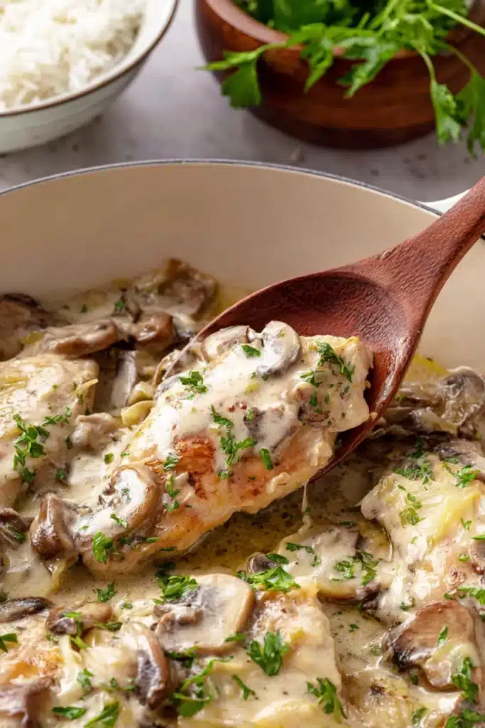 Close-up creamy chicken with mushrooms and parsley in skillet