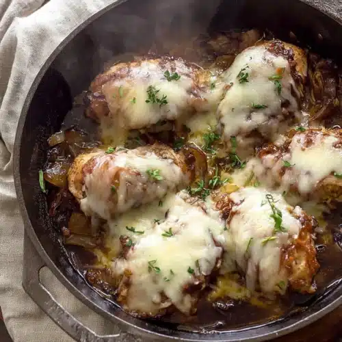 Skillet of French Onion Chicken topped with melted cheese and herbs