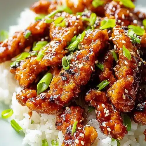 Ginger chicken with glossy sauce over rice topped with green onions