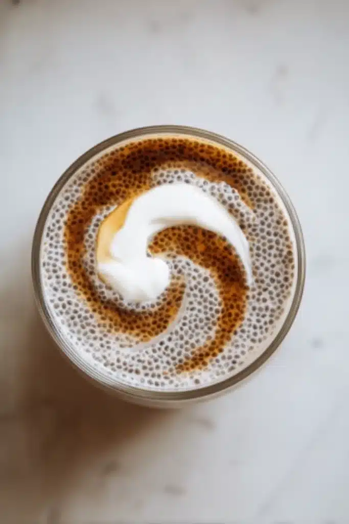 Glass of chocolate chia pudding with maple syrup and coconut cream swirl
