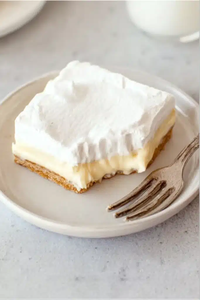 No-bake banana cream pie bar with bite taken, showing creamy layers