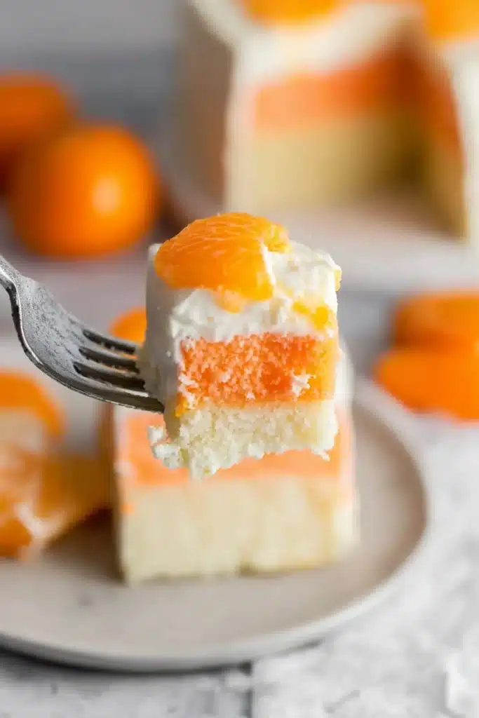 Fork with a bite of orange creamsicle cake showing orange and white layers