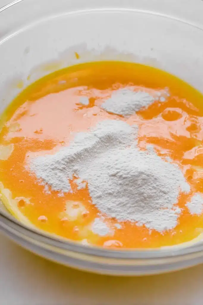 Mixing orange sherbet and pudding in glass bowl for orange creamsicle cake