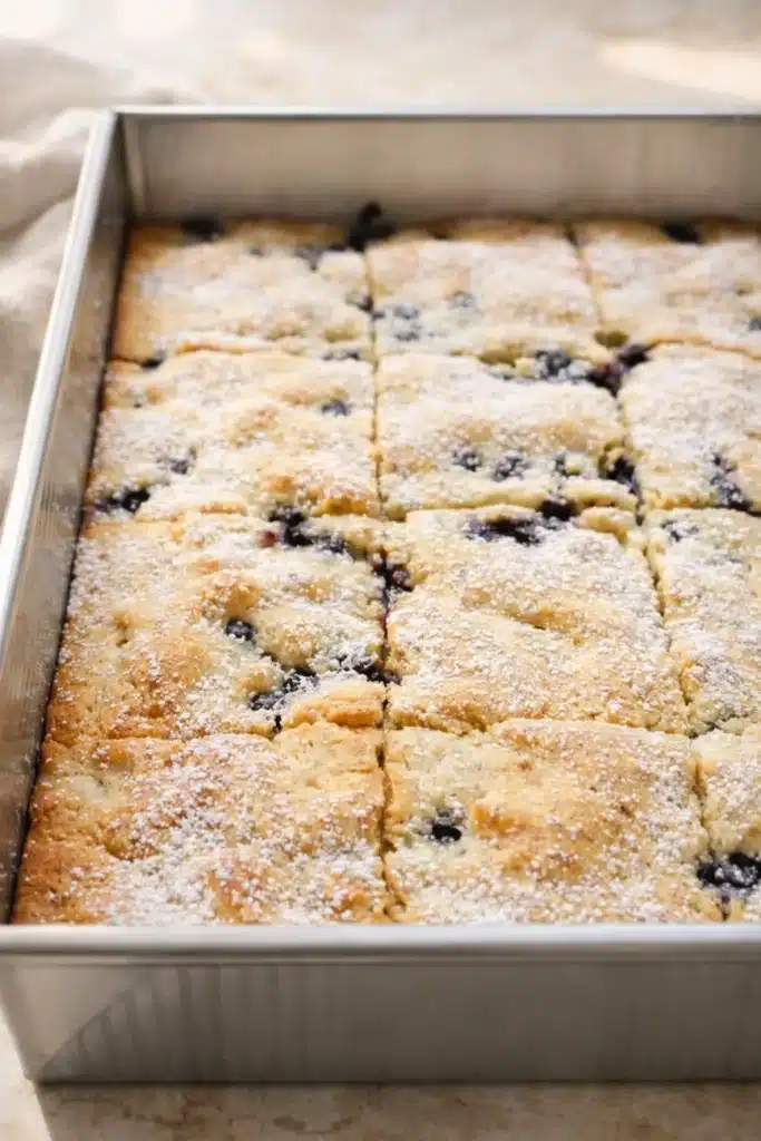 Freshly baked blueberry pancake casserole dusted with powdered sugar in a metal pan