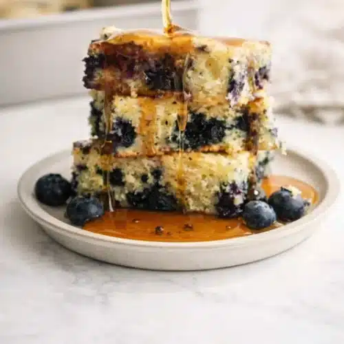 Blueberry pancake casserole stack with syrup drizzle and fresh blueberries