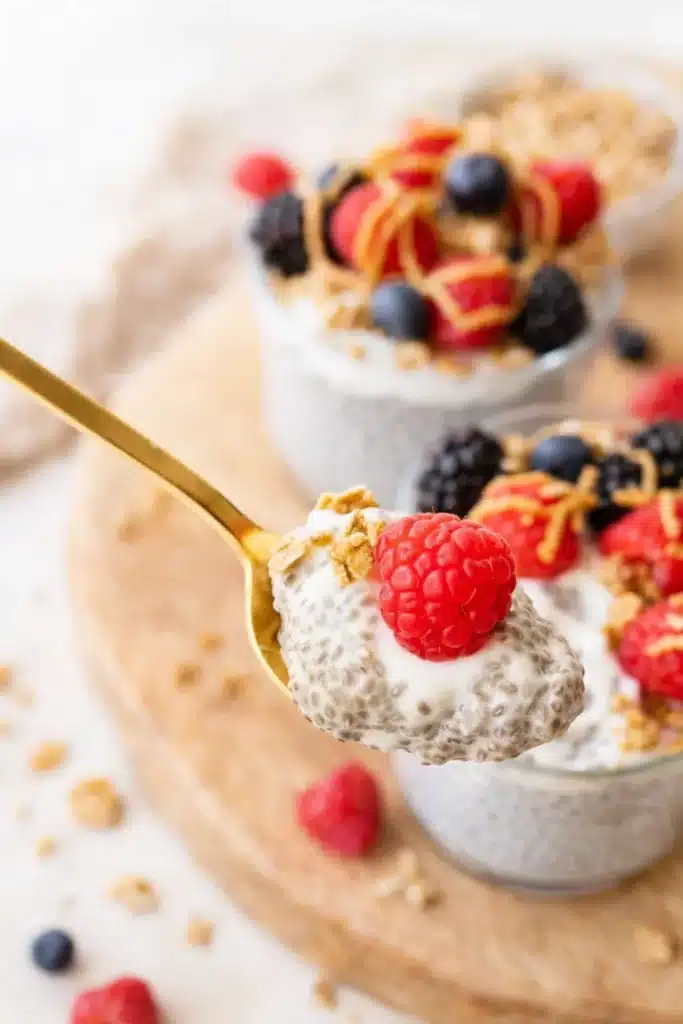 Spoonful of creamy protein chia pudding with raspberry and granola