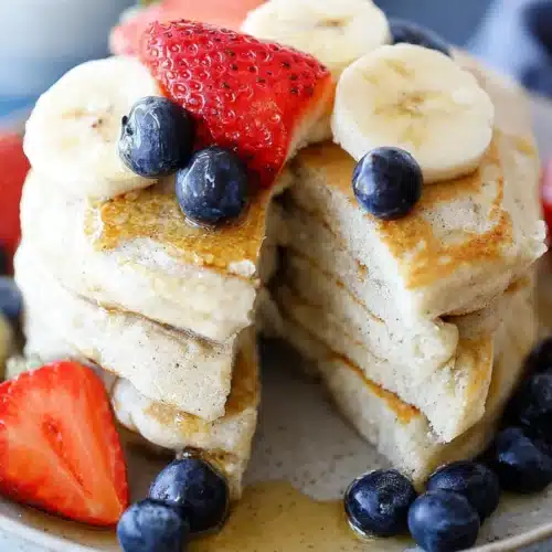 Fluffy protein pancakes with banana, strawberries, blueberries, and maple syrup