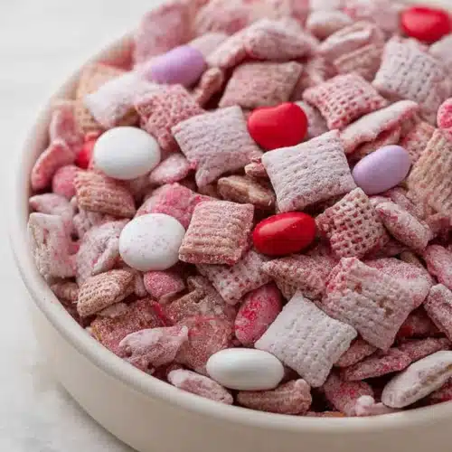 Valentine’s Day muddy buddies snack mix with pink candy and powdered sugar