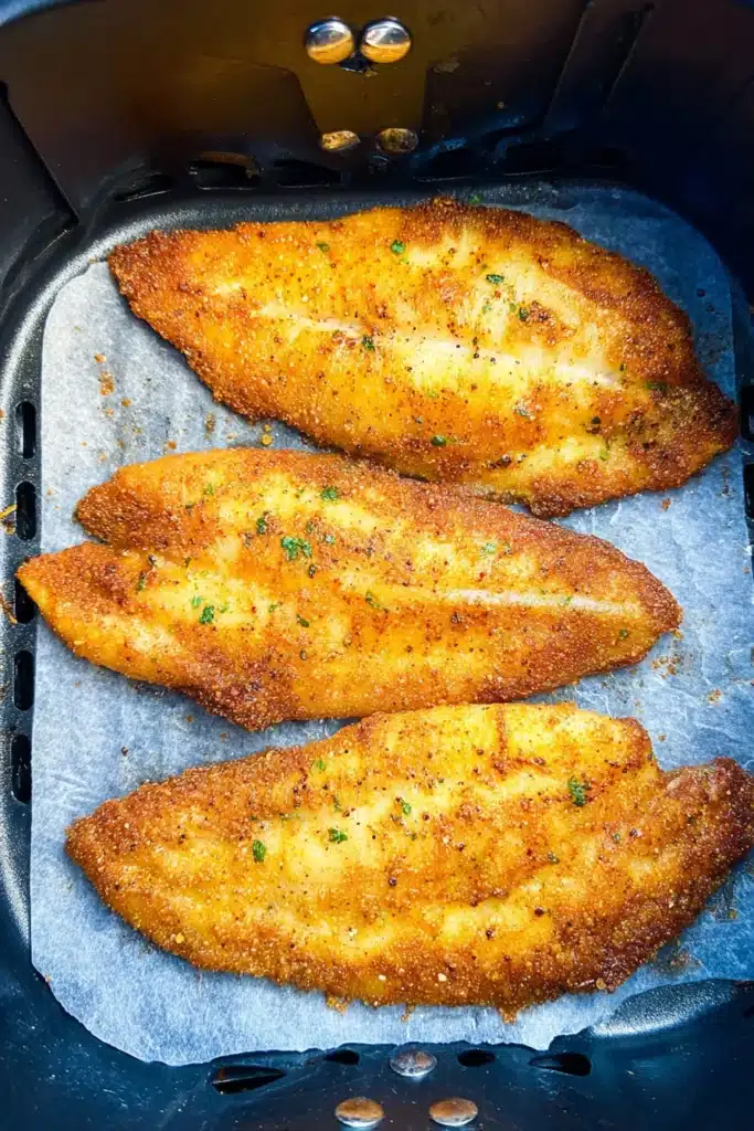 Crispy golden catfish fillets cooking in an air fryer basket