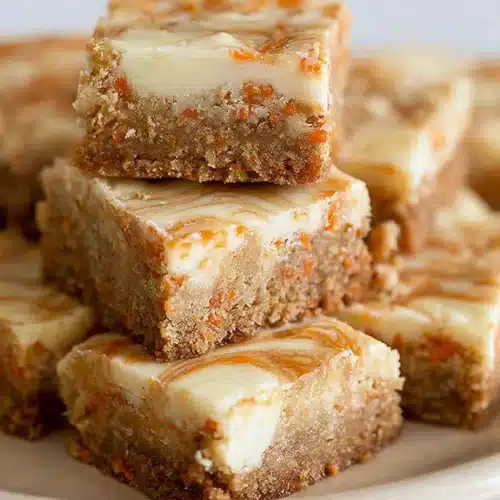 Carrot Cake Bars 5 Stacked carrot cake bars with cheesecake swirl on beige plate