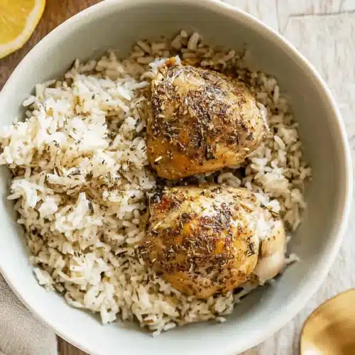 CrockPot Lemon Chicken and Rice 4 Crockpot lemon chicken and rice in gray bowl with fluffy rice and seasoned chicken thighs