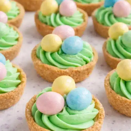 Easter basket sugar cookie cups with green frosting and pastel candy eggs