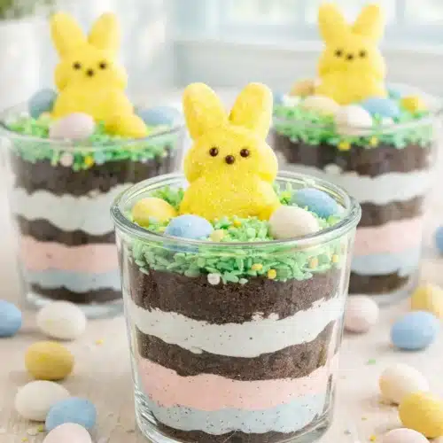 Easter Dirt Cups That Are Fun, Creamy, and Kid Approved 3 Easter dirt cups with pastel pudding layers, Oreo crumbs, and marshmallow Peeps bunny topping