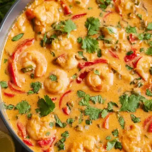 Creamy Thai shrimp soup with coconut curry, shrimp, red peppers, and cilantro in a black pot