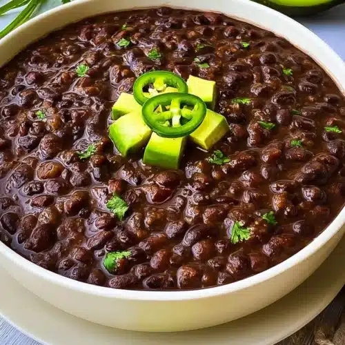 Instant Pot black bean soup topped with avocado and jalapeño slices in a white bowl