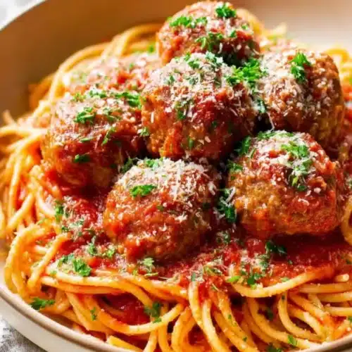 Bowl of Melt-In-Your-Mouth Italian Meatballs topped with marinara sauce, Parmesan, and parsley