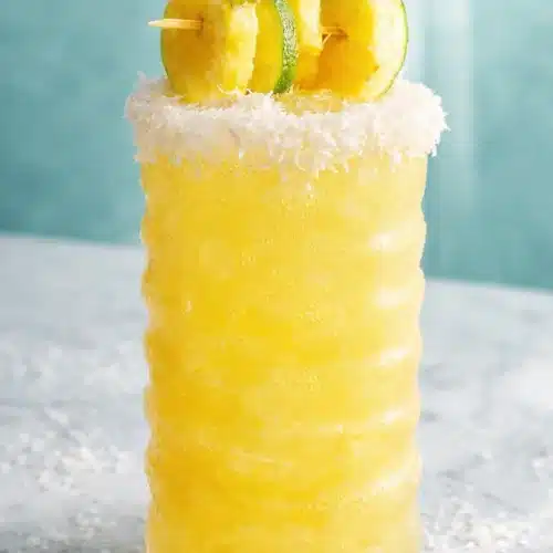 Non Alcoholic Piña Colada Punch That’s Quick, Creamy, and Refreshing 3 Non alcoholic piña colada punch in tall glass with coconut rim and pineapple garnish