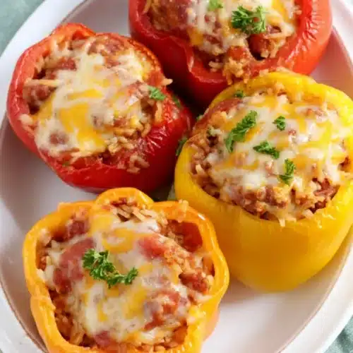 Slow cooker stuffed peppers with rice, sausage, and melted cheese on white plate