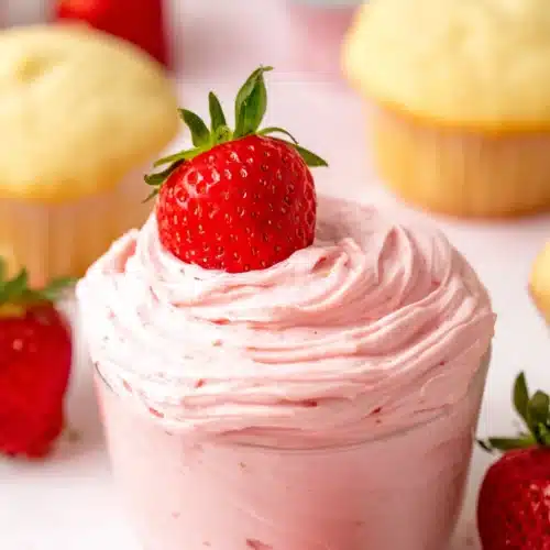 Strawberry Buttercream Frosting in a glass topped with a fresh strawberry