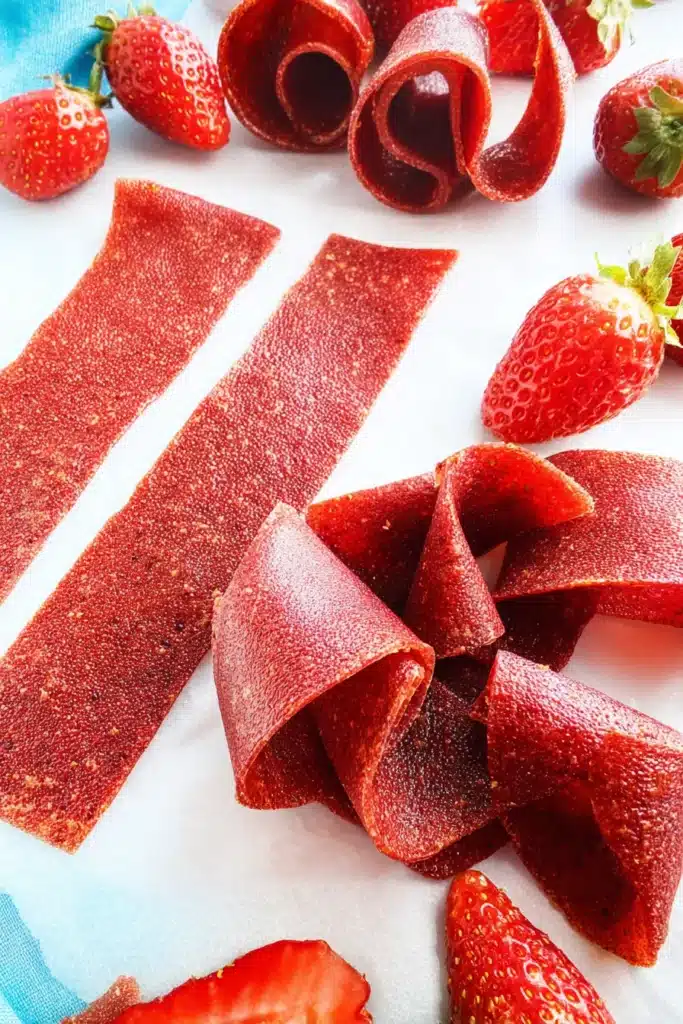 Finished Strawberry Fruit Roll-Ups cut and rolled on parchment paper