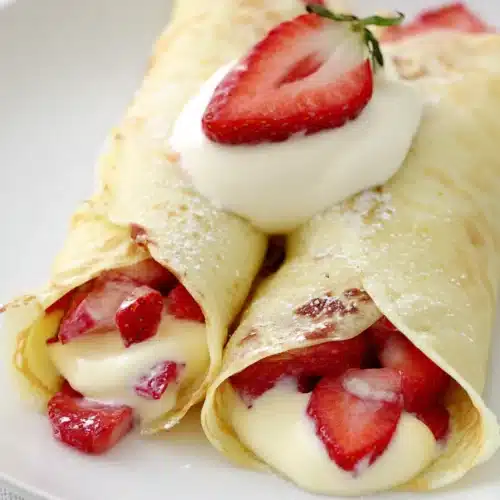 Strawberry & Lemon Cream Crepe with fresh strawberries and whipped cream on a white plate