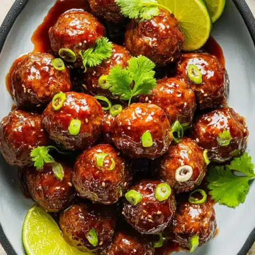 Teriyaki Meatballs Recipe That’s Quick, Juicy, and Flavorful 4 Glossy teriyaki meatballs with green onions and lime in ceramic bowl