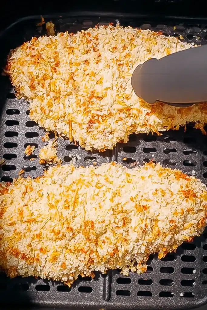 Breaded chicken cutlets in air fryer basket for Air Fryer Chicken Parmesan