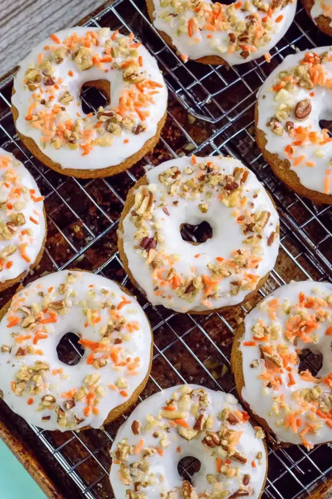 Carrot Cake Donuts That Are Soft, Spiced, and Perfect for Easter 2 Carrot Cake Donuts with cream cheese frosting, walnuts, and orange sprinkles cooling on a wire rack