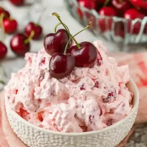 Cherry Cheesecake Fluff in a white bowl topped with fresh red cherries