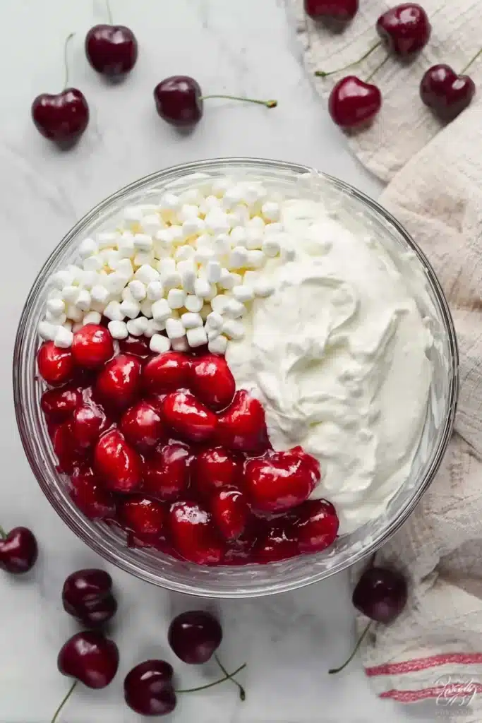 Cherry Cheesecake Fluff ingredients in glass bowl with marshmallows and cherry filling