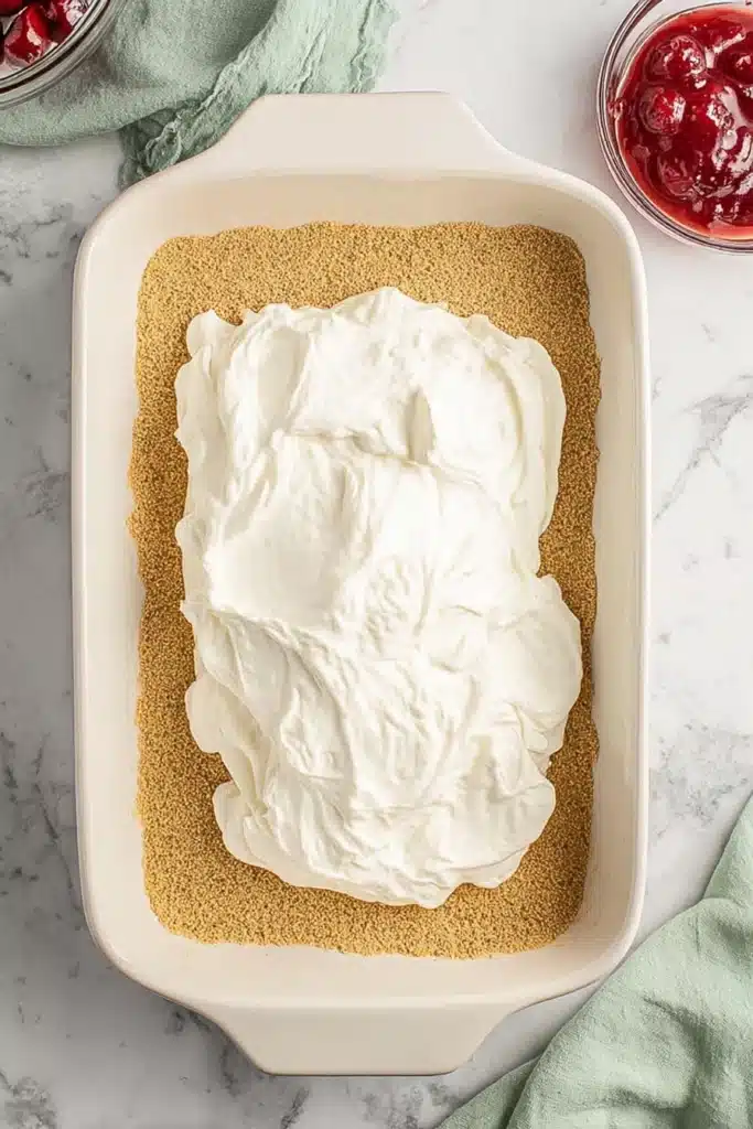 Cherry Delight Easy Creamy No Bake Dessert 3 Cherry Delight cream cheese filling spread over graham cracker crust in baking dish