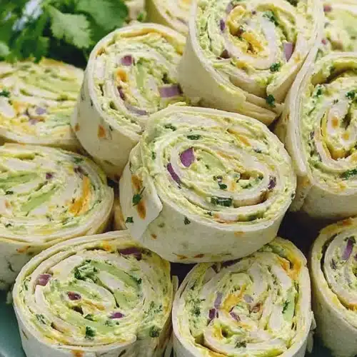 Chicken avocado salad roll ups sliced into pinwheels on a green plate