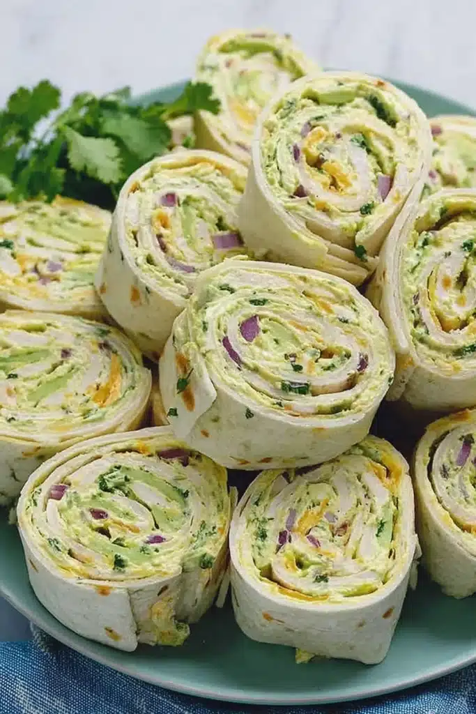Chicken avocado salad roll ups sliced into pinwheels on a green plate