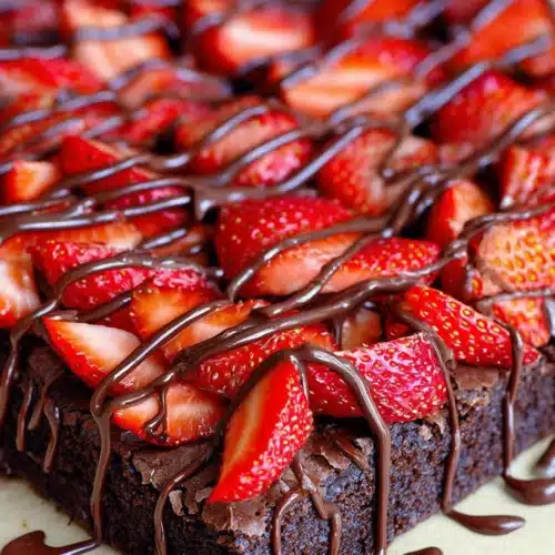 Chocolate strawberry brownies topped with fresh strawberries and chocolate drizzle